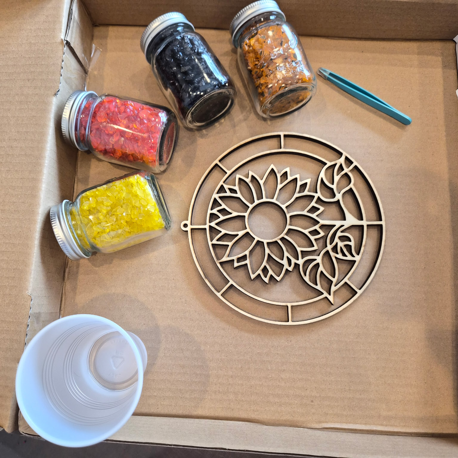 DIY crushed glass resin suncatcher kit featuring a sunflower mold, colorful crushed glass jars, and tools for the workshop at The Shoppes Off Trade in Greer, SC.